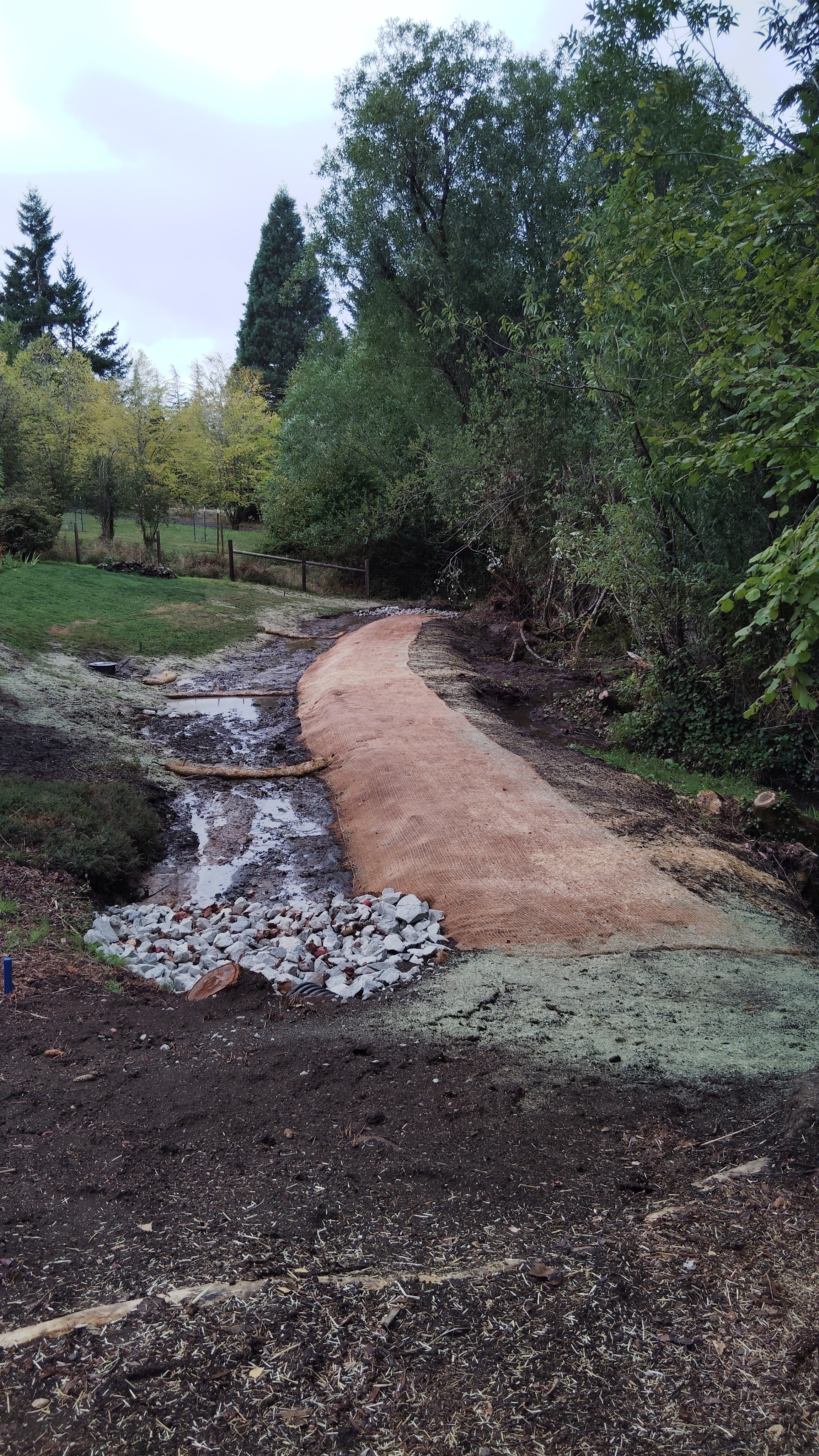 Erosion control matting installed along sloped pathway with rock stabilization
